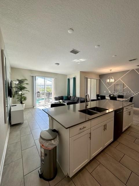 kitchen featuring a notable chandelier, white cabinets, sink, dishwasher, and a center island with sink