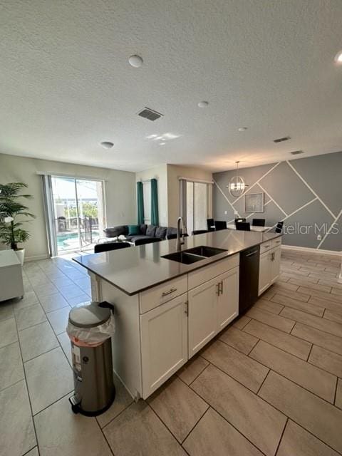 kitchen featuring black dishwasher, white cabinetry, a center island with sink, and sink