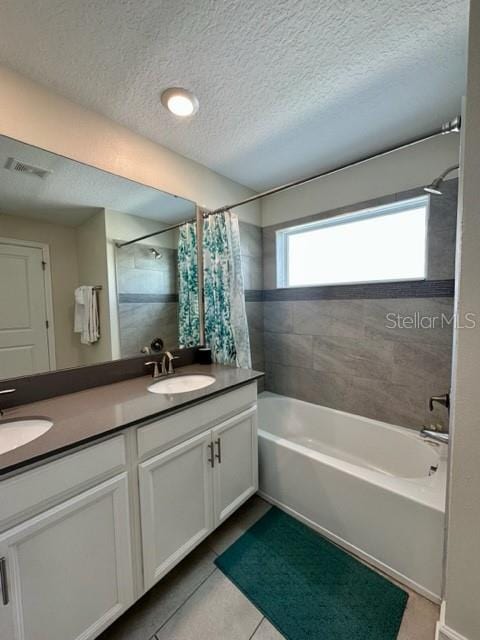 bathroom featuring dual vanity, tile patterned floors, a textured ceiling, and shower / bath combo