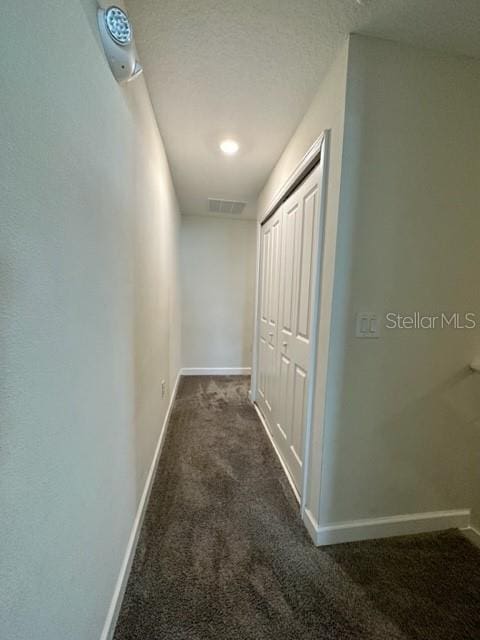 hallway featuring dark colored carpet