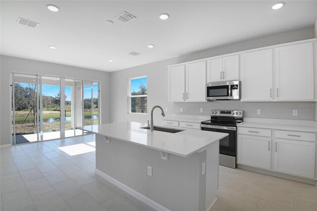 kitchen featuring sink, white cabinetry, appliances with stainless steel finishes, and a kitchen island with sink