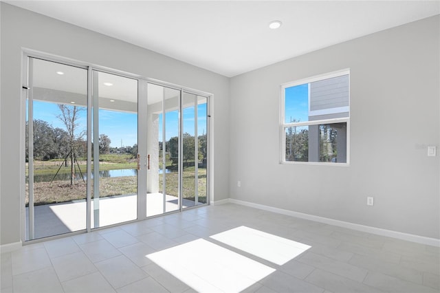 empty room with light tile patterned floors and a water view