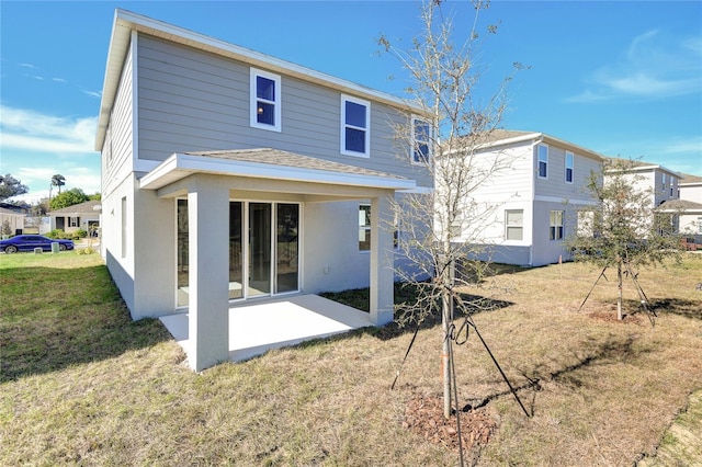 back of property with a lawn and a patio