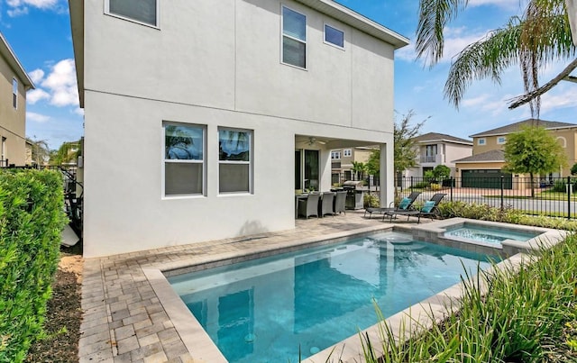 back of property with a swimming pool with hot tub and a patio