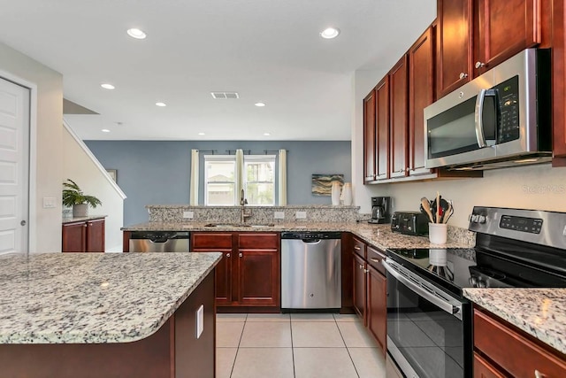 kitchen featuring appliances with stainless steel finishes, sink, light stone countertops, kitchen peninsula, and light tile patterned flooring