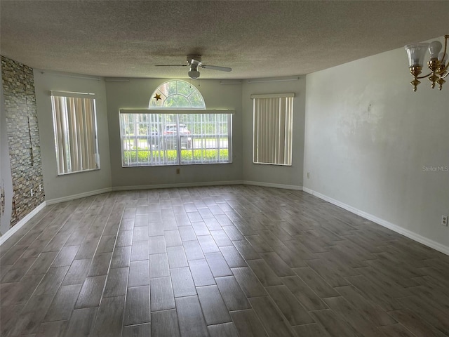 empty room with ceiling fan with notable chandelier, a textured ceiling, and dark hardwood / wood-style flooring