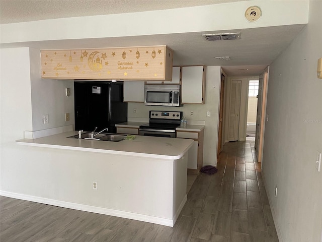 kitchen featuring dark wood-type flooring, appliances with stainless steel finishes, sink, and kitchen peninsula