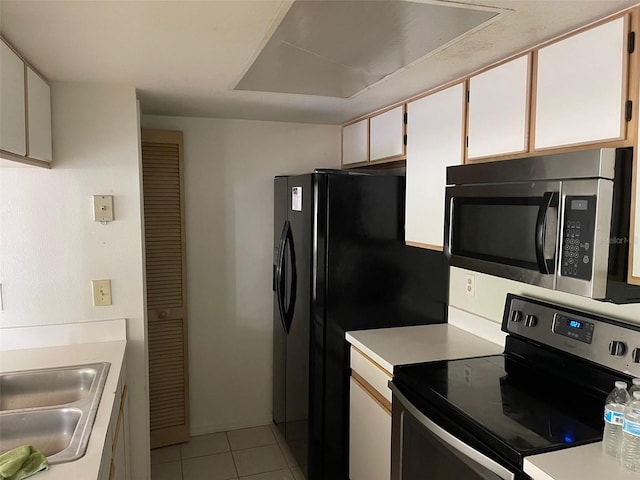 kitchen with sink, stainless steel appliances, light tile patterned floors, and white cabinets