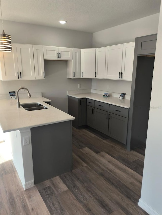 kitchen featuring dark wood-style flooring, white cabinets, a sink, and gray cabinetry