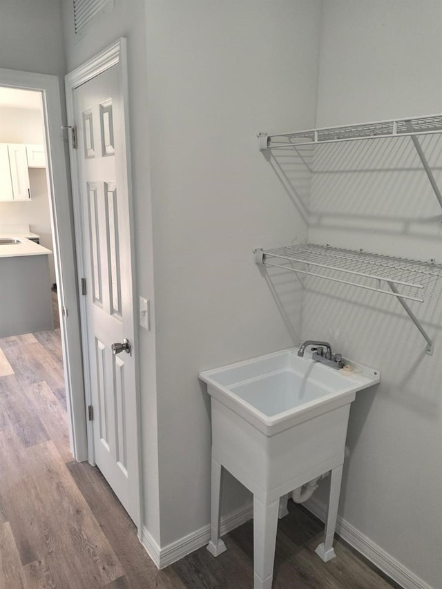 laundry area featuring wood finished floors and baseboards