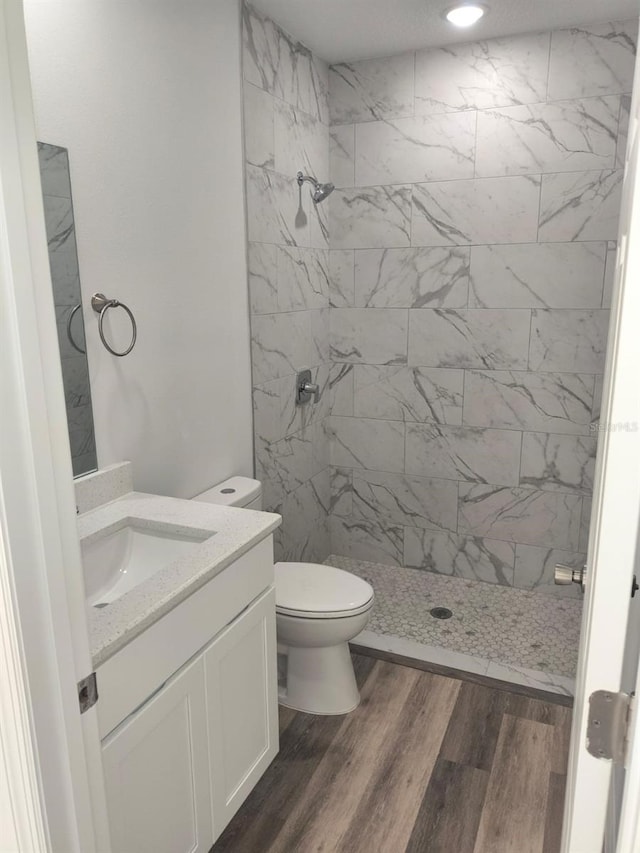 bathroom featuring toilet, a shower stall, wood finished floors, and vanity