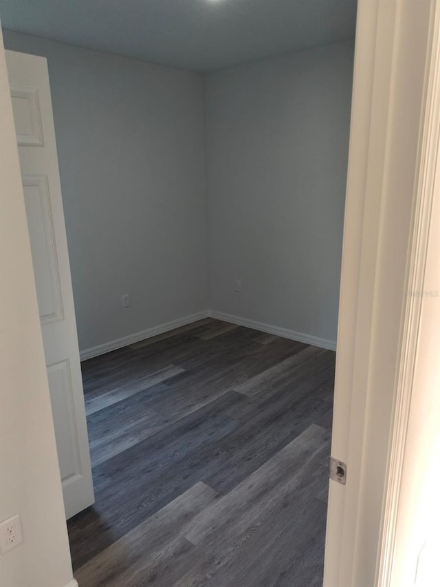 spare room with dark wood-style flooring and baseboards