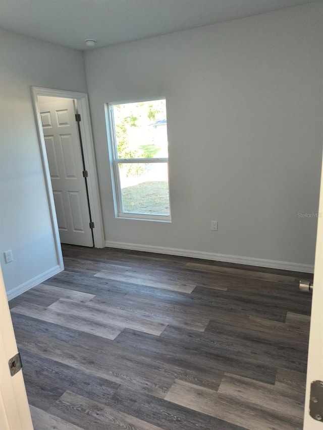 empty room featuring dark wood-style flooring and baseboards