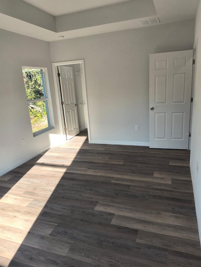 spare room featuring dark wood-style floors, visible vents, and baseboards