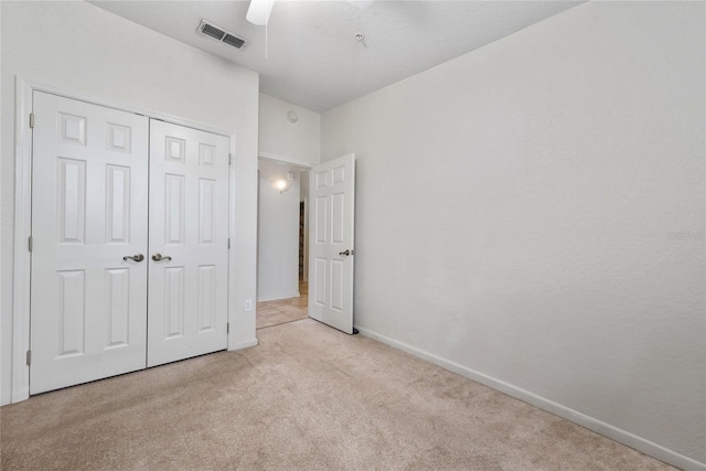 unfurnished bedroom featuring light carpet, a closet, and ceiling fan