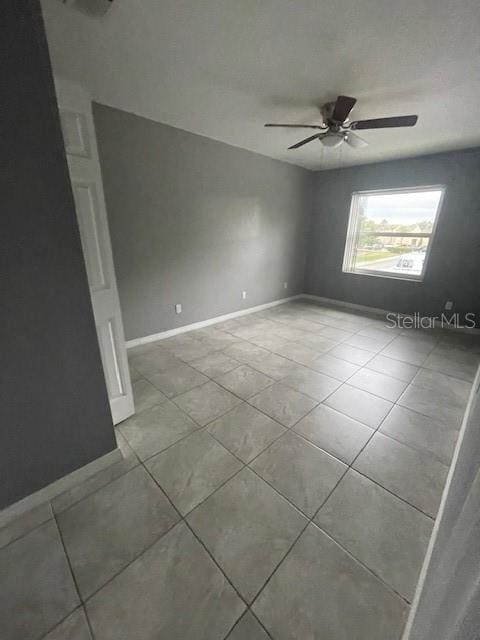 tiled empty room featuring ceiling fan