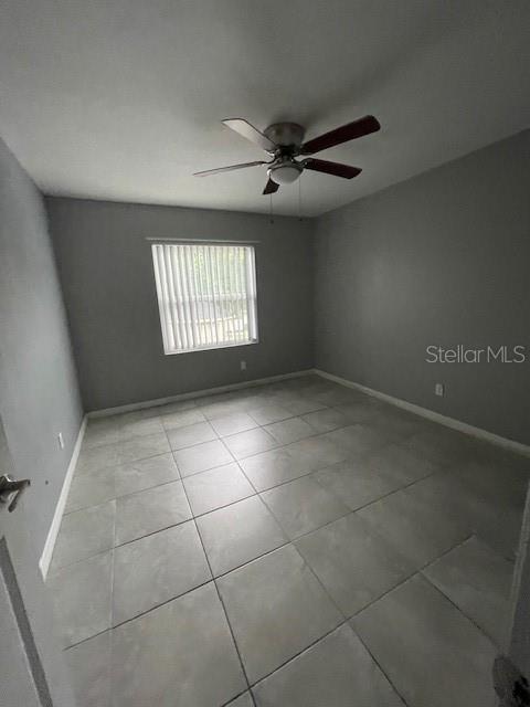 tiled empty room featuring ceiling fan