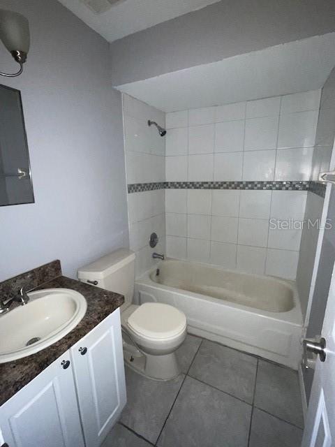 full bathroom featuring toilet, tile patterned floors, tiled shower / bath, and vanity