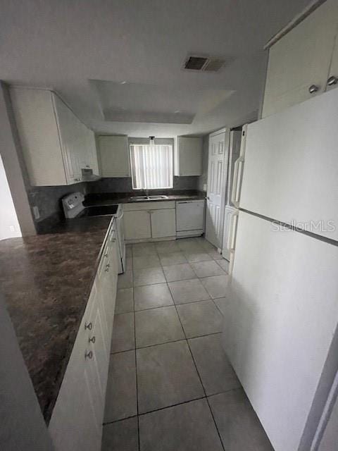 kitchen featuring white cabinets, sink, white appliances, and light tile patterned flooring