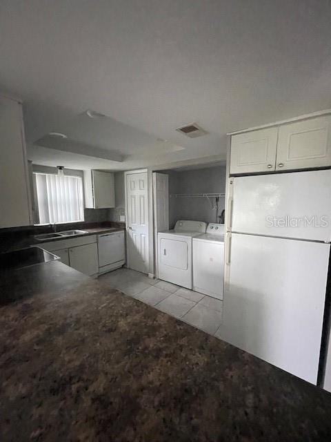 kitchen with sink, light tile patterned floors, white appliances, washing machine and clothes dryer, and white cabinets