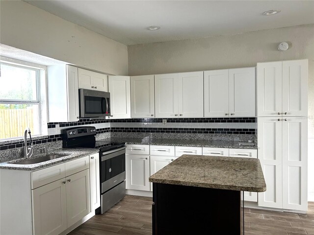 kitchen featuring white cabinetry, stainless steel appliances, decorative backsplash, sink, and a center island