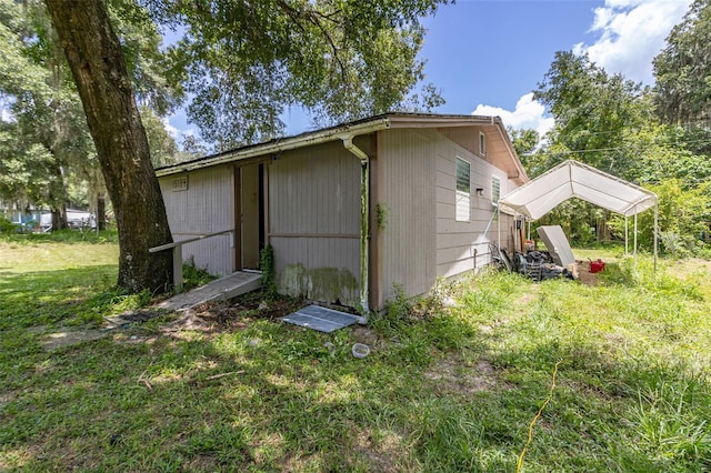 view of side of home featuring an outbuilding, a carport, and a lawn