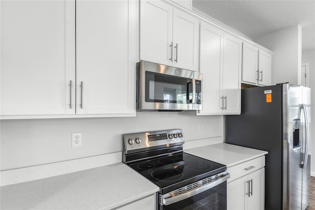 kitchen with appliances with stainless steel finishes, white cabinetry, and a textured ceiling