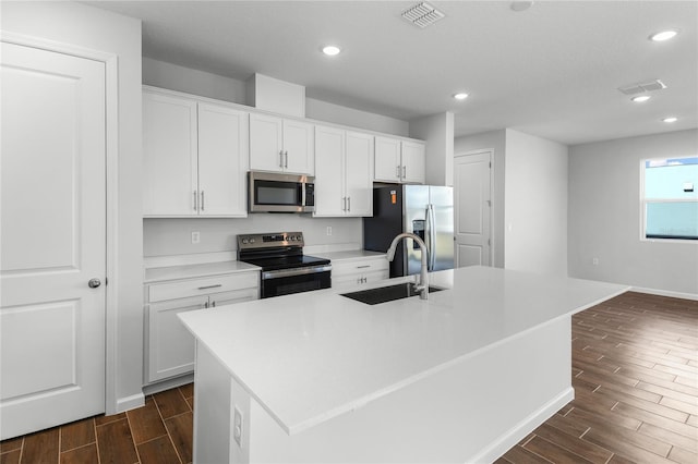 kitchen featuring white cabinets, sink, stainless steel appliances, and a center island with sink