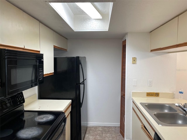 kitchen with light tile patterned floors, black appliances, sink, and cream cabinets