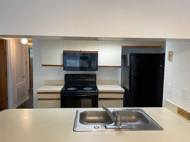 kitchen with sink, black appliances, and white cabinets