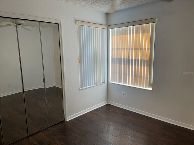 unfurnished bedroom with a textured ceiling, a closet, and wood-type flooring