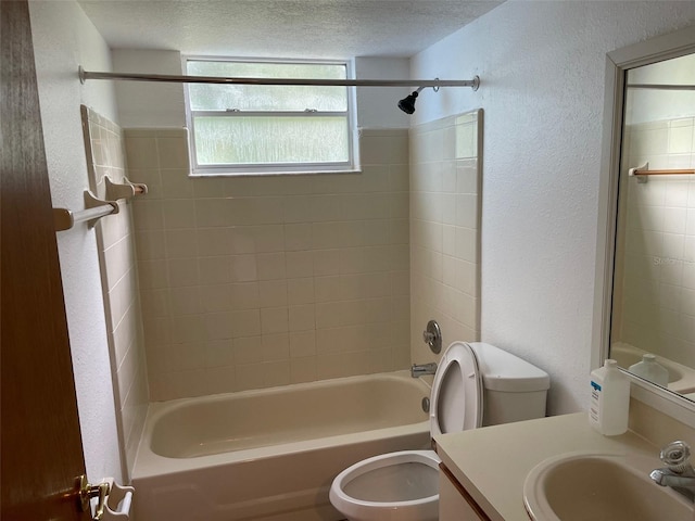 full bathroom featuring vanity, tiled shower / bath, toilet, and a textured ceiling