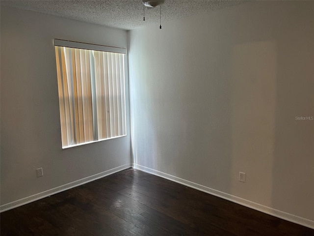 empty room with a textured ceiling and dark wood-type flooring