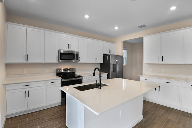 kitchen featuring white cabinetry, stainless steel appliances, and a kitchen island with sink