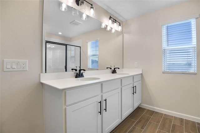 bathroom featuring a shower with door and vanity