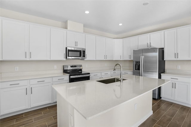 kitchen with white cabinets, appliances with stainless steel finishes, and a kitchen island with sink