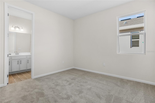 unfurnished bedroom featuring light carpet, sink, and ensuite bath