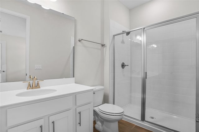 bathroom with a shower with shower door, vanity, and toilet