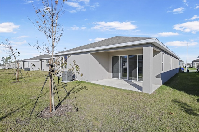 rear view of property with a patio area, a yard, and central AC