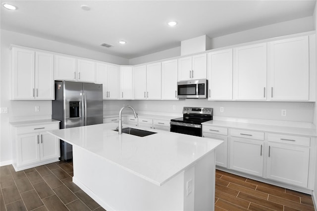 kitchen with sink, white cabinets, stainless steel appliances, and a kitchen island with sink