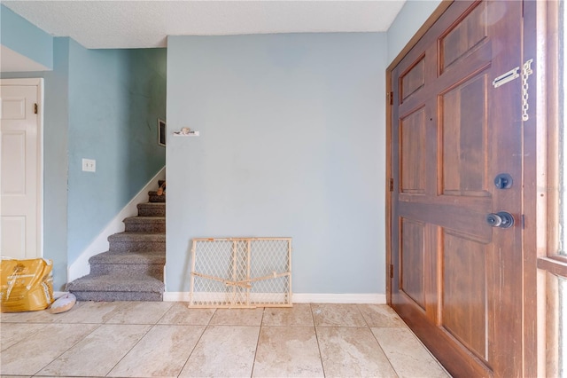 foyer with a textured ceiling and light tile patterned floors