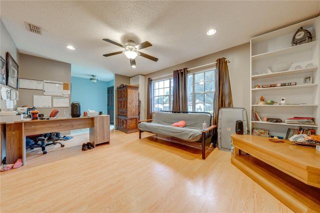 bedroom with ceiling fan, a textured ceiling, and light hardwood / wood-style flooring