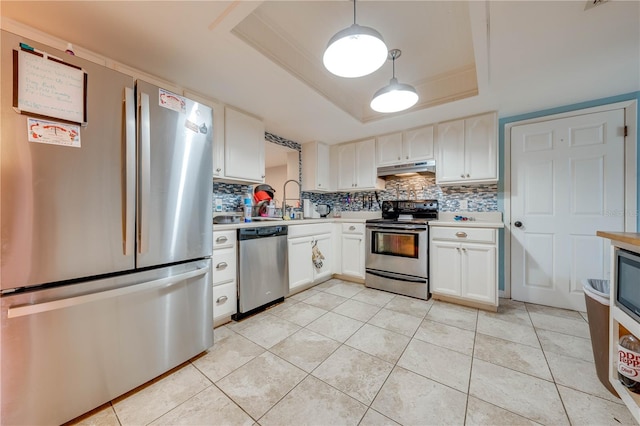 kitchen with stainless steel appliances, decorative light fixtures, tasteful backsplash, and a tray ceiling