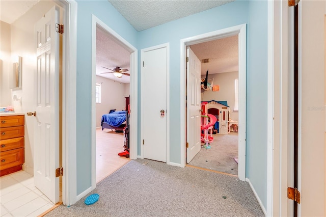 hall with light carpet and a textured ceiling