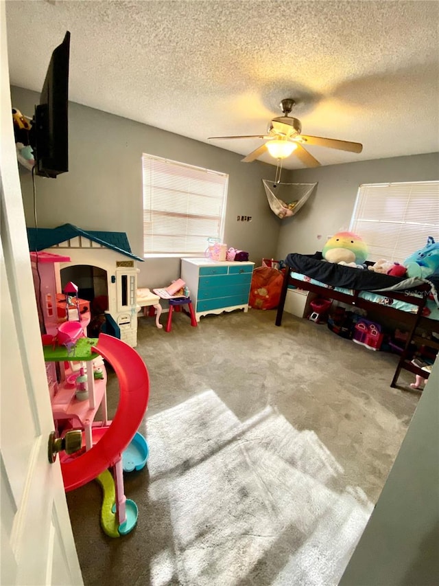 game room featuring ceiling fan, carpet flooring, and a textured ceiling