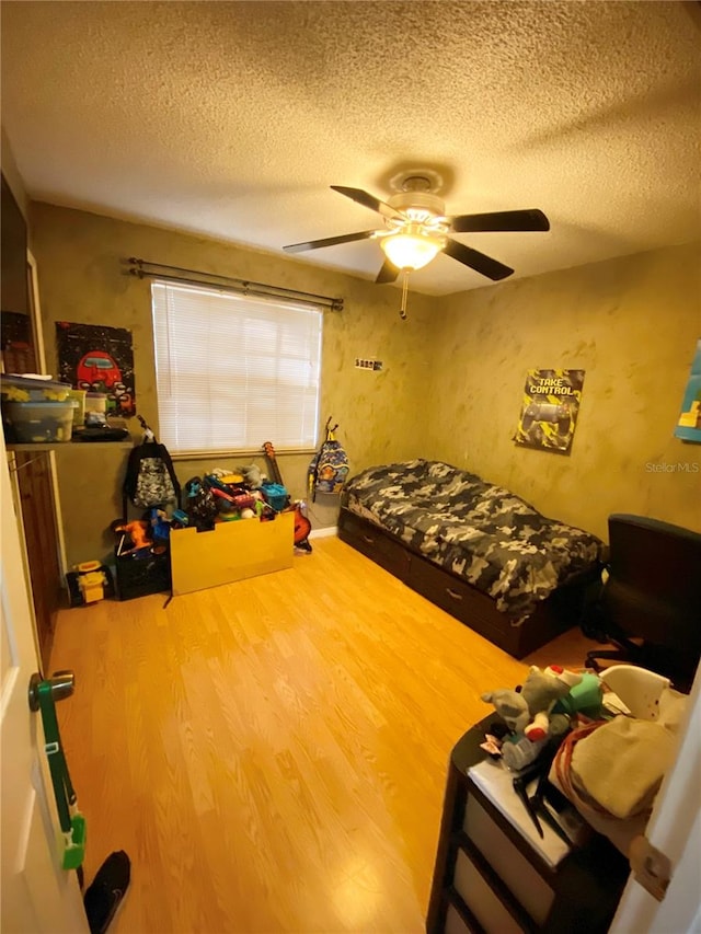 bedroom with a textured ceiling, ceiling fan, and wood-type flooring