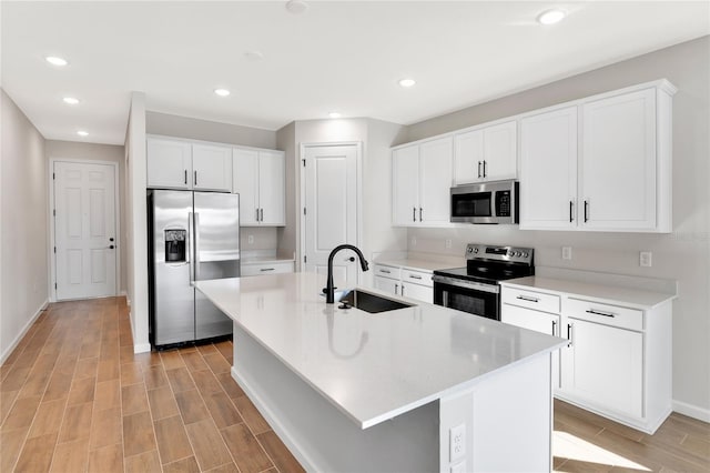 kitchen featuring white cabinets, stainless steel appliances, sink, a kitchen island with sink, and a breakfast bar area