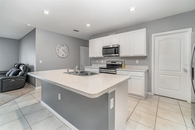 kitchen featuring light tile patterned flooring, an island with sink, and stainless steel appliances