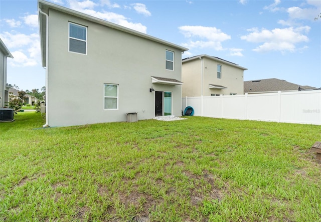 rear view of property featuring a lawn and central AC unit