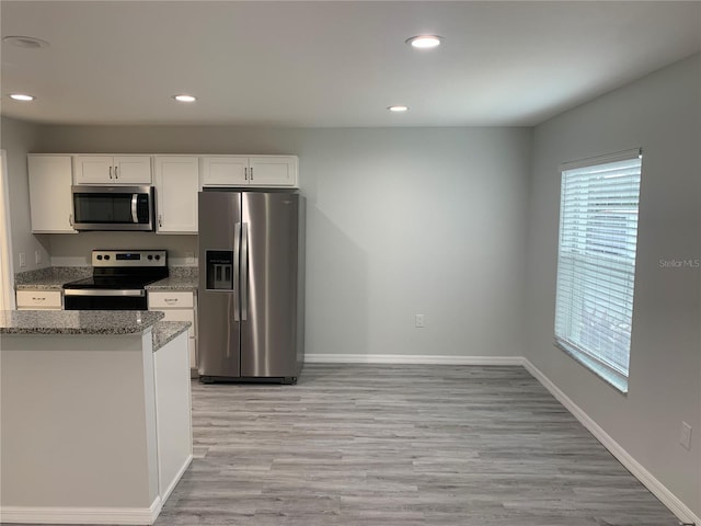 kitchen with light stone countertops, stainless steel appliances, light hardwood / wood-style floors, and white cabinets